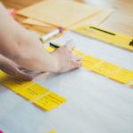 Jemand klebt Post-Its auf ein Posterpapier